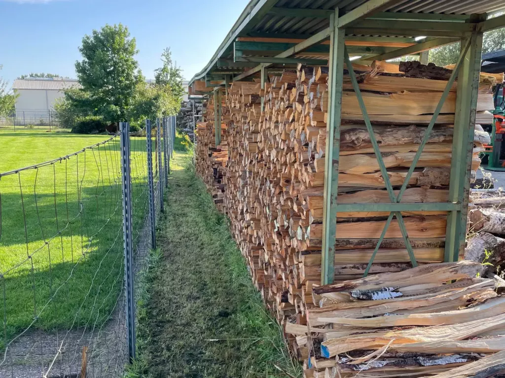 Gespaltenes Holz lagert luftig unter dem Dach der Trockenhalle