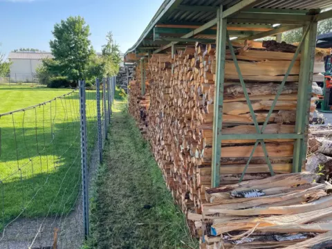 Gespaltenes Holz lagert luftig unter dem Dach der Trockenhalle